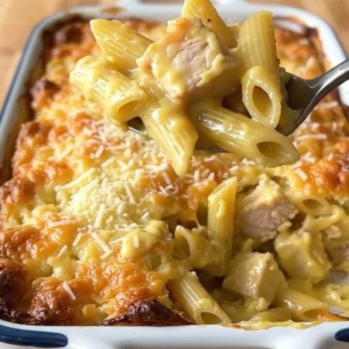 A large white enameled rectangular baker filled with a creamy lemon pepper chicken penne bake on a butcher-block counter.