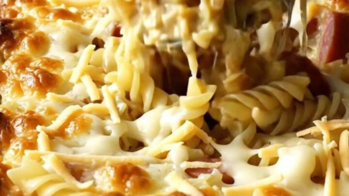 A golden, bubbling Polish Reuben Kielbasa Pasta Bake in a white ceramic dish on a beige countertop.
