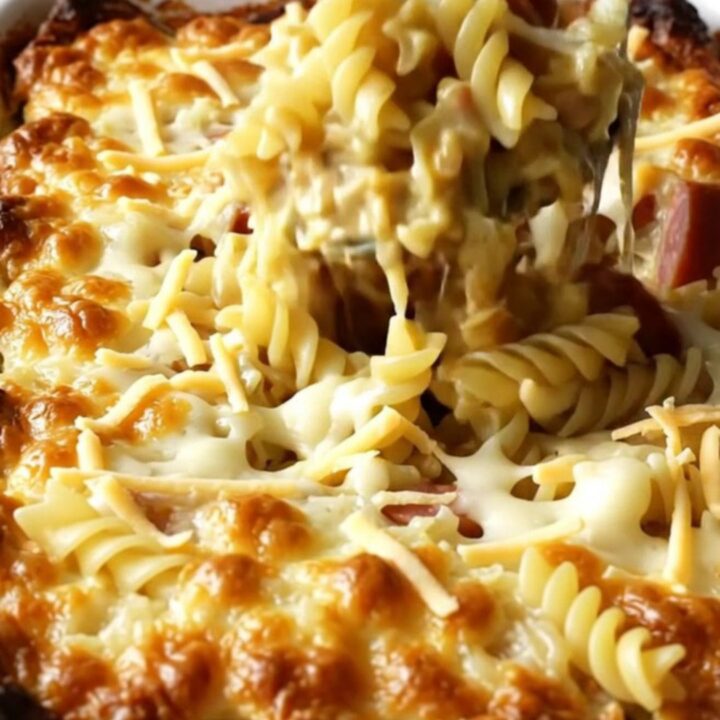 A golden, bubbling Polish Reuben Kielbasa Pasta Bake in a white ceramic dish on a beige countertop.