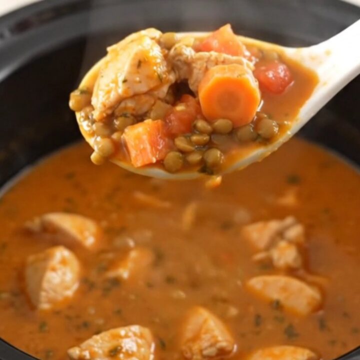 A bowl of warm, hearty chicken and lentil stew with visible carrot coins and herbs.
