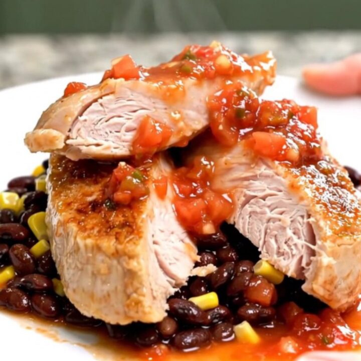 A close-up of tender, slow-cooked turkey tenderloins served with black beans and corn on a white plate.