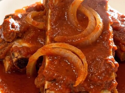 A close-up of tender, slow-cooked boneless country-style ribs coated in a rich red enchilada sauce.