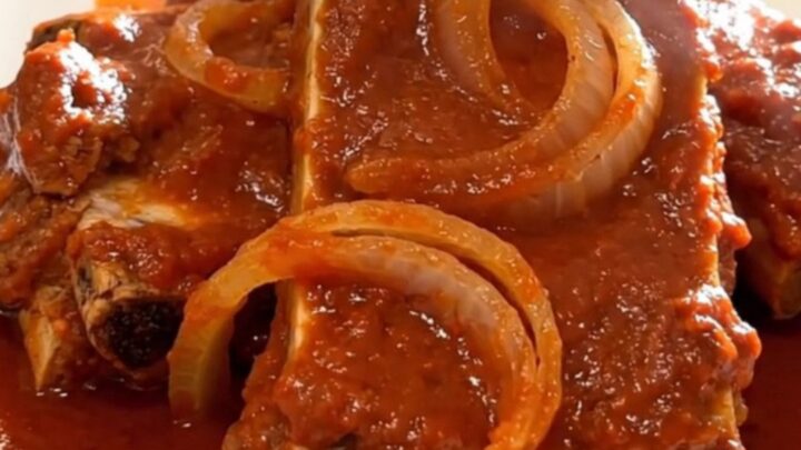 A close-up of tender, slow-cooked boneless country-style ribs coated in a rich red enchilada sauce.