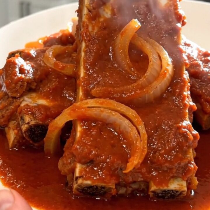 A close-up of tender, slow-cooked boneless country-style ribs coated in a rich red enchilada sauce.