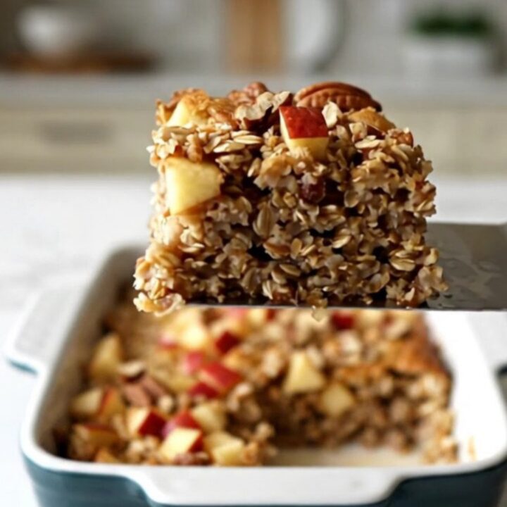 A top-down view of a rectangular ceramic dish filled with baked oatmeal, topped with diced red apples and pecans.