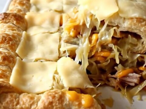 A golden brown Turkey Reuben Crescent Bake in a white ceramic dish sitting on a speckled countertop.
