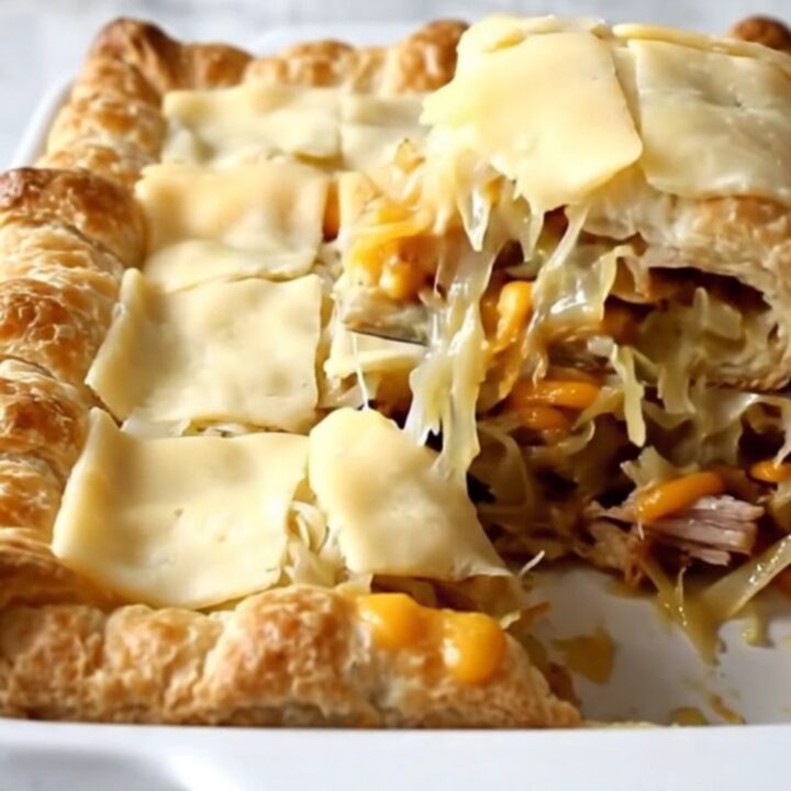 A golden brown Turkey Reuben Crescent Bake in a white ceramic dish sitting on a speckled countertop.