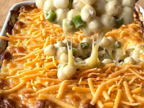 A top-down view of a rectangular white ceramic dish filled with a creamy, golden-brown baked hominy casserole.