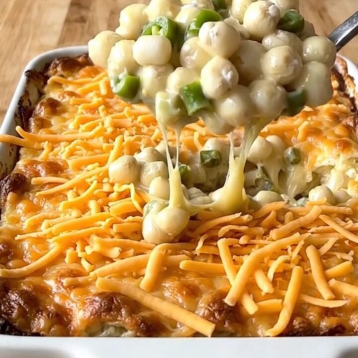 A top-down view of a rectangular white ceramic dish filled with a creamy, golden-brown baked hominy casserole.