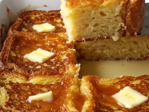 A rectangular ceramic dish filled with golden-brown, custard-soaked French toast slices with a caramelized sugar crust.