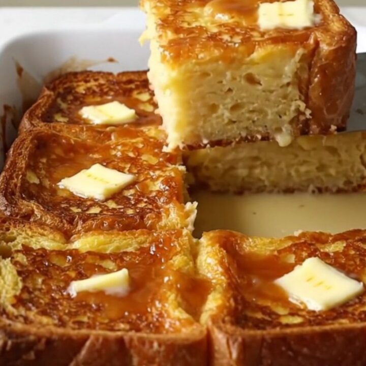 A rectangular ceramic dish filled with golden-brown, custard-soaked French toast slices with a caramelized sugar crust.