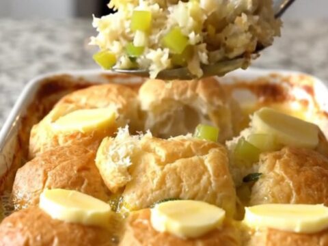 A golden-brown sweet roll stuffing bake in a white ceramic dish on a speckled granite surface.