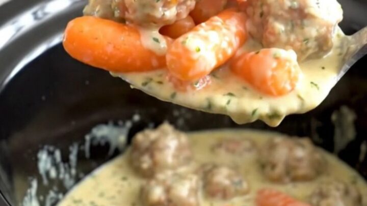 A slow cooker filled with turkey meatballs and baby carrots coated in a creamy herb cheese sauce.