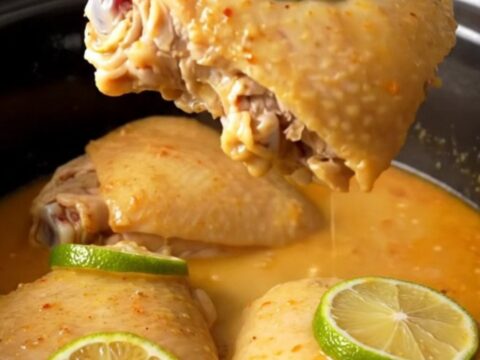 A top-down view of six raw chicken thighs arranged in a white ceramic slow cooker insert, ready to be seasoned.