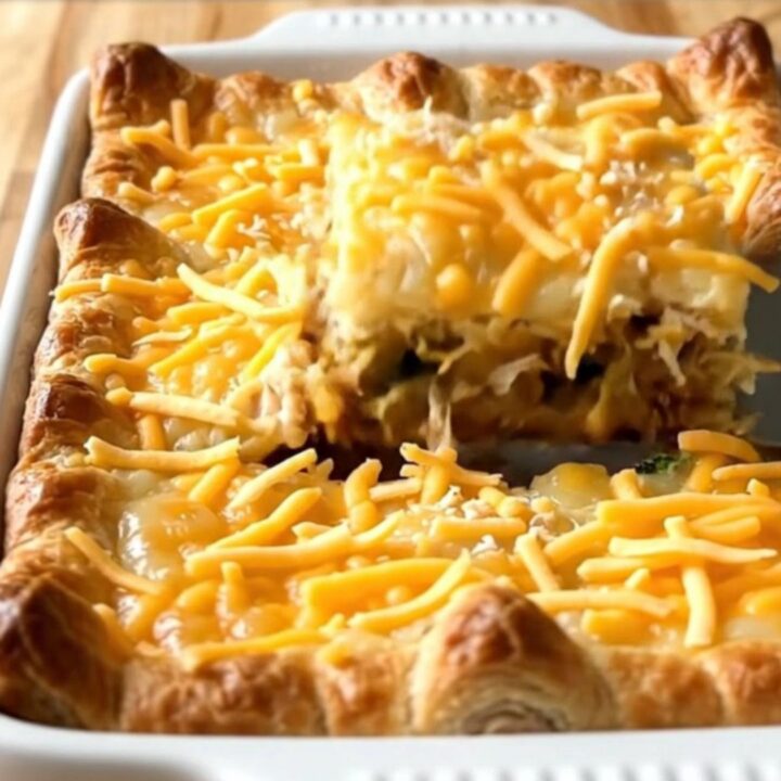 A golden-brown chicken and broccoli crescent square lifted from a 9x13 baking dish, showing flaky layers and creamy filling.