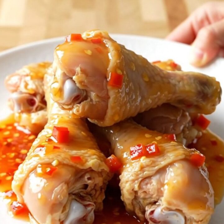 Slow cooker apricot habanero chicken drumsticks with a glossy, thick glaze on a white serving plate.