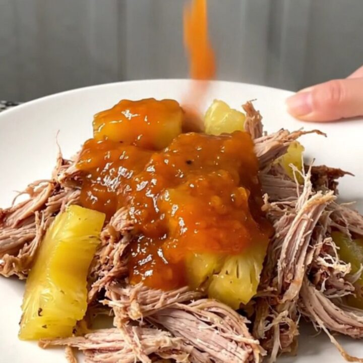 A close-up of pineapple habanero pulled pork sliders on a platter with steam rising.