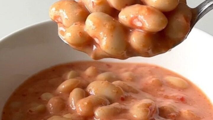 A close-up of creamy butter beans in a rich pink vodka sauce topped with grated Parmesan cheese.