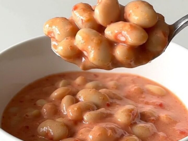 A close-up of creamy butter beans in a rich pink vodka sauce topped with grated Parmesan cheese.