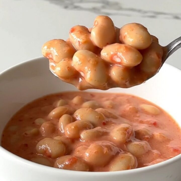 A close-up of creamy butter beans in a rich pink vodka sauce topped with grated Parmesan cheese.