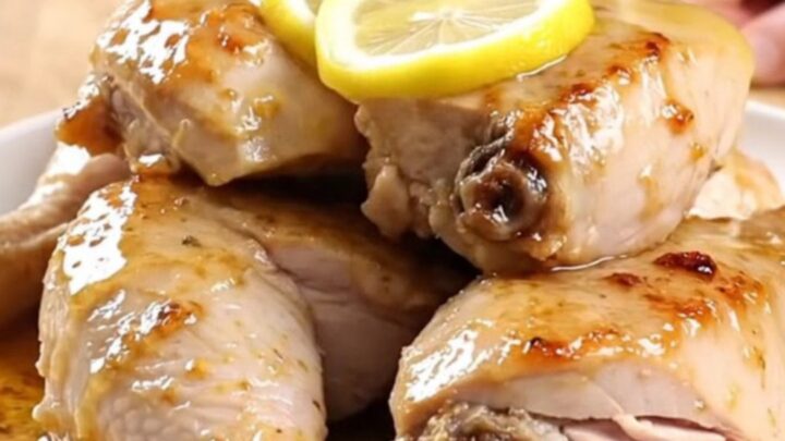 A plate of tender, slow-cooked lemon pepper turkey breast garnished with soft lemon slices.