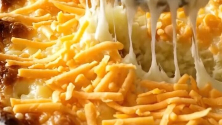 A top-down view of a rectangular baking dish filled with creamy mashed potatoes topped with melted cheddar cheese.