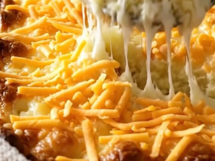 A top-down view of a rectangular baking dish filled with creamy mashed potatoes topped with melted cheddar cheese.