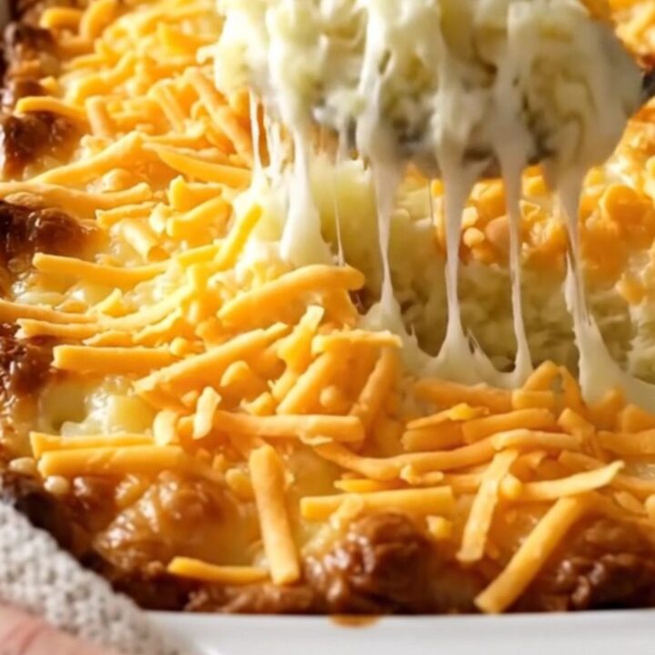 A top-down view of a rectangular baking dish filled with creamy mashed potatoes topped with melted cheddar cheese.