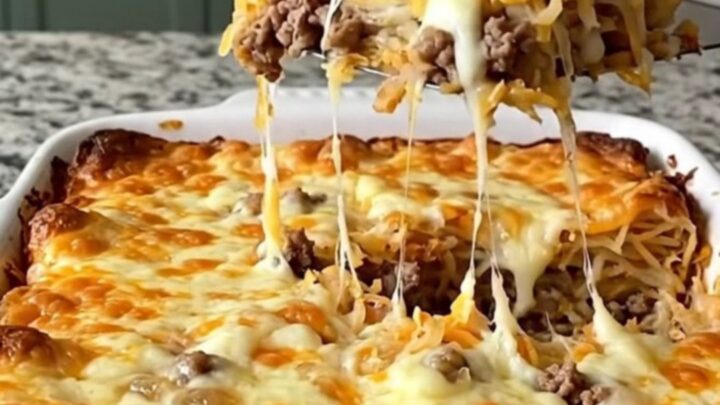 A golden, bubbling bacon cheeseburger hash brown bake in a rectangular ceramic dish on a light granite counter.