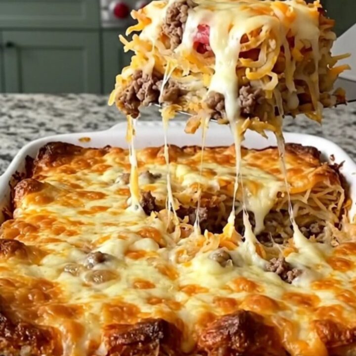 A golden, bubbling bacon cheeseburger hash brown bake in a rectangular ceramic dish on a light granite counter.