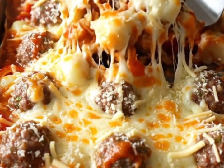 A sheet pan filled with golden gnocchi, meatballs, and peppers covered in melted mozzarella.