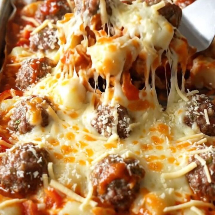 A sheet pan filled with golden gnocchi, meatballs, and peppers covered in melted mozzarella.