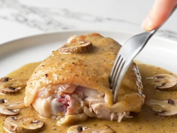 A close-up of tender chicken thighs in a creamy mushroom Marsala sauce served on a white plate.