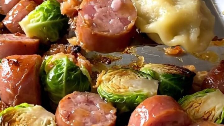 A sheet pan filled with golden-brown kielbasa coins, puffy pierogies