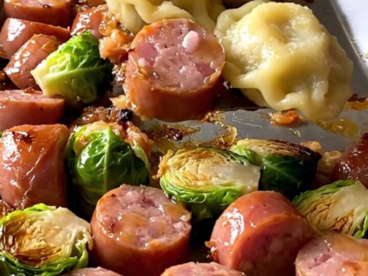 A sheet pan filled with golden-brown kielbasa coins, puffy pierogies