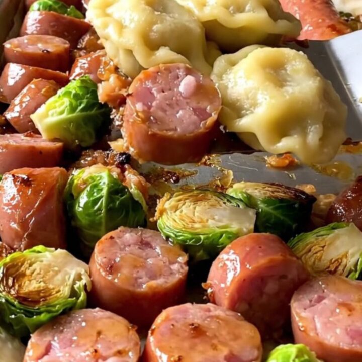 A sheet pan filled with golden-brown kielbasa coins, puffy pierogies