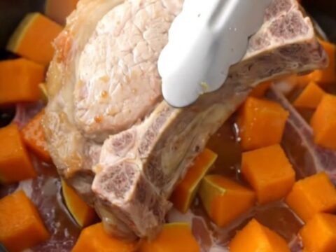 A close-up of tender bone-in pork chops and cubes of butternut squash coated in a glossy brown sugar glaze.
