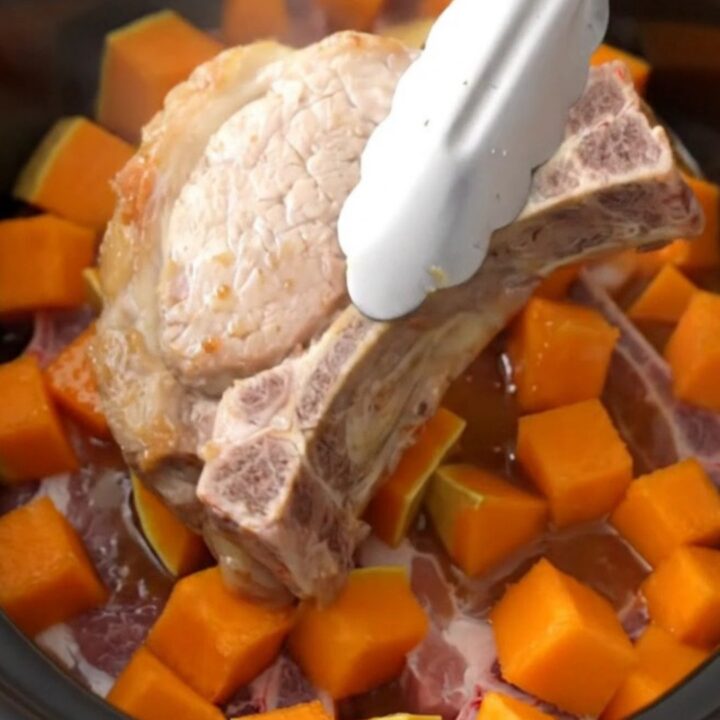 A close-up of tender bone-in pork chops and cubes of butternut squash coated in a glossy brown sugar glaze.