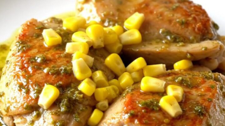 A close-up of tender chili lime chicken thighs served with sweet corn on a white plate.
