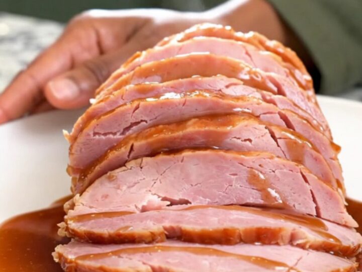 A spiral-sliced ham in a slow cooker covered with a dark, glossy molasses and gingerbread spice glaze.