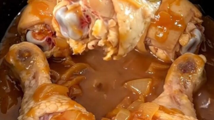 A close-up of slow-cooked chicken drumsticks in a rich, dark brown sugar and tomato chili sauce.