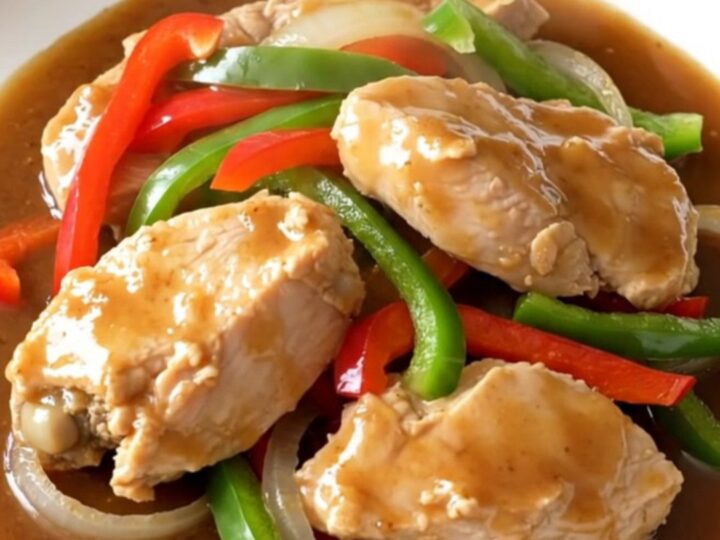 A close-up of slow cooker chicken pepper steak served on a white plate with visible steam.