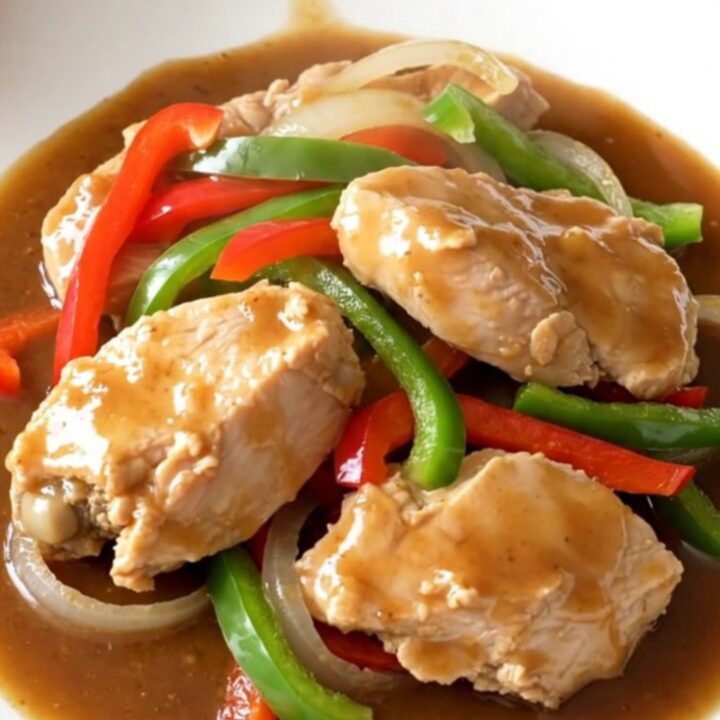 A close-up of slow cooker chicken pepper steak served on a white plate with visible steam.