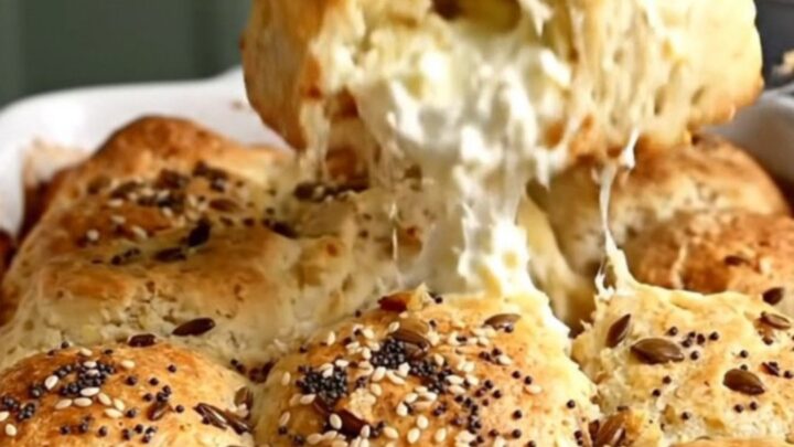 A top-down view of a golden-brown everything bagel pull-apart biscuit bake in a white ceramic dish.
