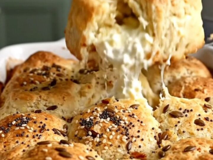 A top-down view of a golden-brown everything bagel pull-apart biscuit bake in a white ceramic dish.