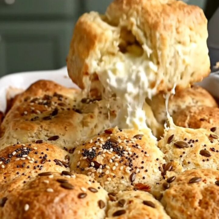 A top-down view of a golden-brown everything bagel pull-apart biscuit bake in a white ceramic dish.