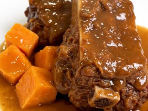 A ceramic slow cooker filled with raw boneless pork ribs and sweet potato chunks ready to be cooked.