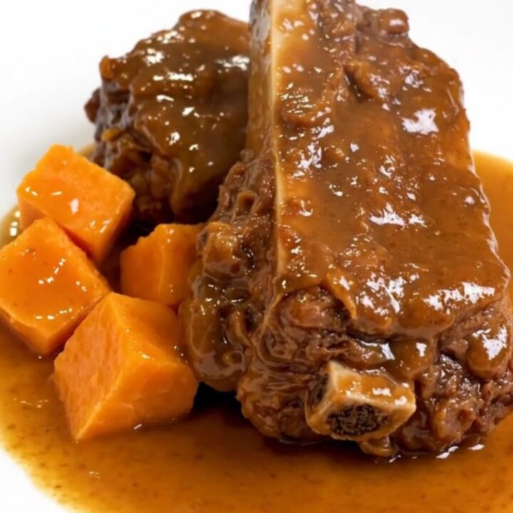 A ceramic slow cooker filled with raw boneless pork ribs and sweet potato chunks ready to be cooked.