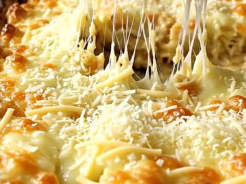 A top-down view of thick green cabbage wedges in a ceramic dish topped with melted mozzarella and parmesan cheese.
