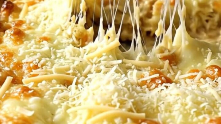 A top-down view of thick green cabbage wedges in a ceramic dish topped with melted mozzarella and parmesan cheese.